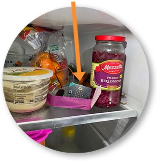 A Micro:bit sitting on a refrigerator shelf between food containers, marked with an orange arrow.